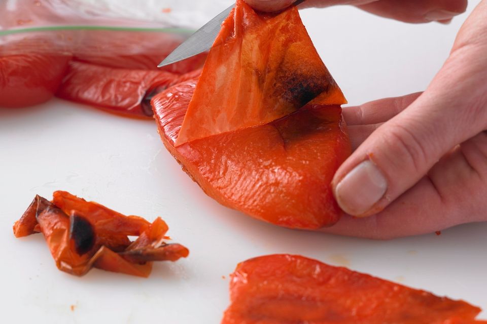Paprika häuten: Hände ziehen die Haut von Paprika ab