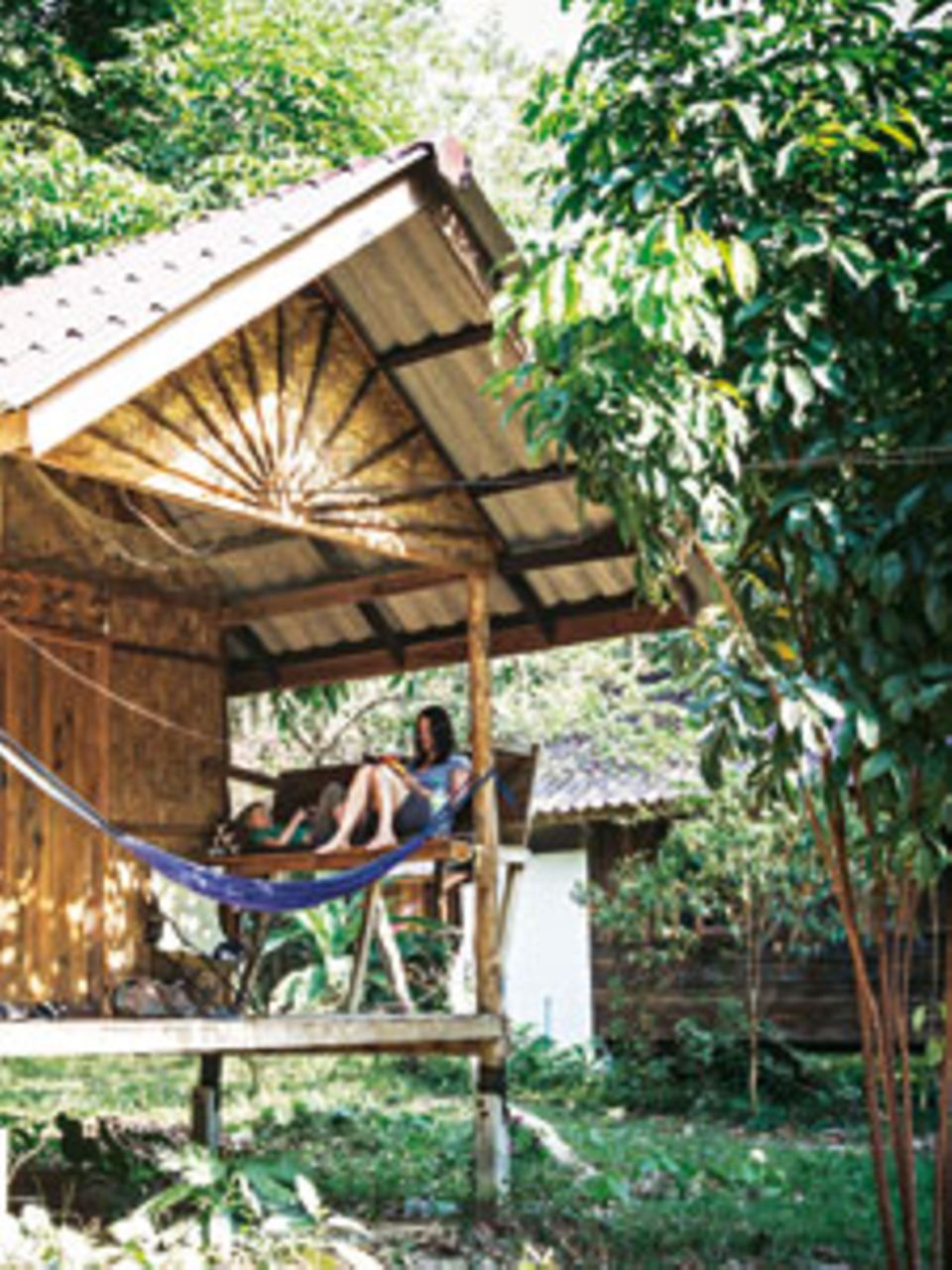 Siesta Thailandia: Während die Mittagssonne auf die Insel Koh Phayam brennt, verziehen sich Susanne und Fred zum Lesen auf ihre Veranda. Wenn die Mama Glück hat, liest der Sohn auch mal vor