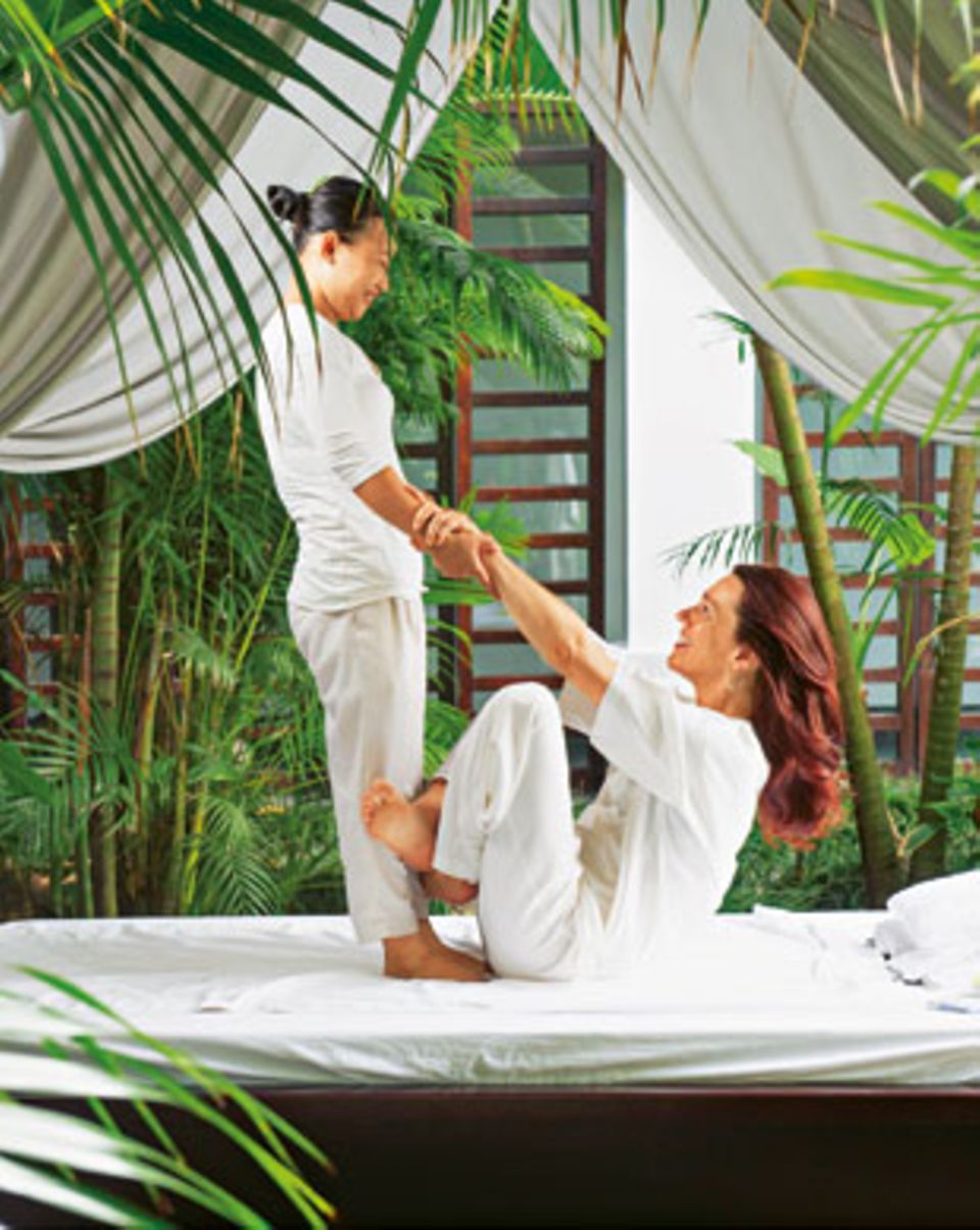 Wellness in Vietnam: Arme langziehen: Bei der Thai-Massage im Spa-Garten des Resorts "Fusion Maia Da Nang" bringt Therapeutin Mai vollen Einsatz und klettert gleich mit auf die Liege.