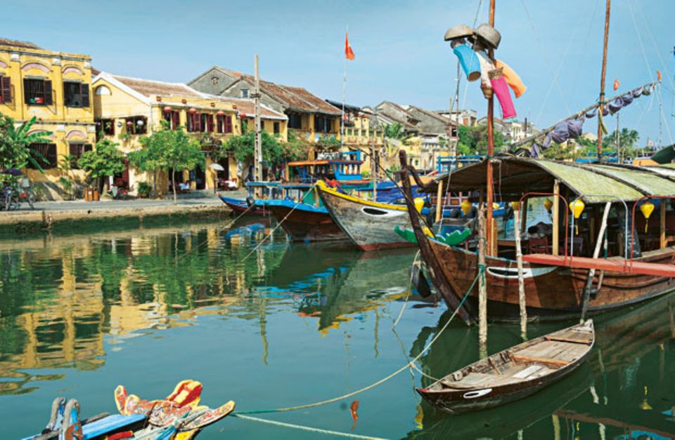 Wellness in Vietnam: Ruhiger Fluss: Der Thu-Bon-Fluss in Hoi An schmückt sich mit bunten Holzbooten und schenkt der Altstadt eine Promenade mit Cafés und Restaurants.