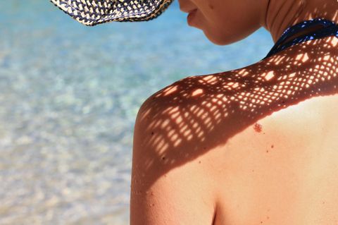 Frau mit Hut am Strand in der prallen Sonne