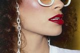 Das brasilianische Model Rio trägt eine weiße Retro-Sonnenbrille mit Brillenkette und rotem Lippenstift.