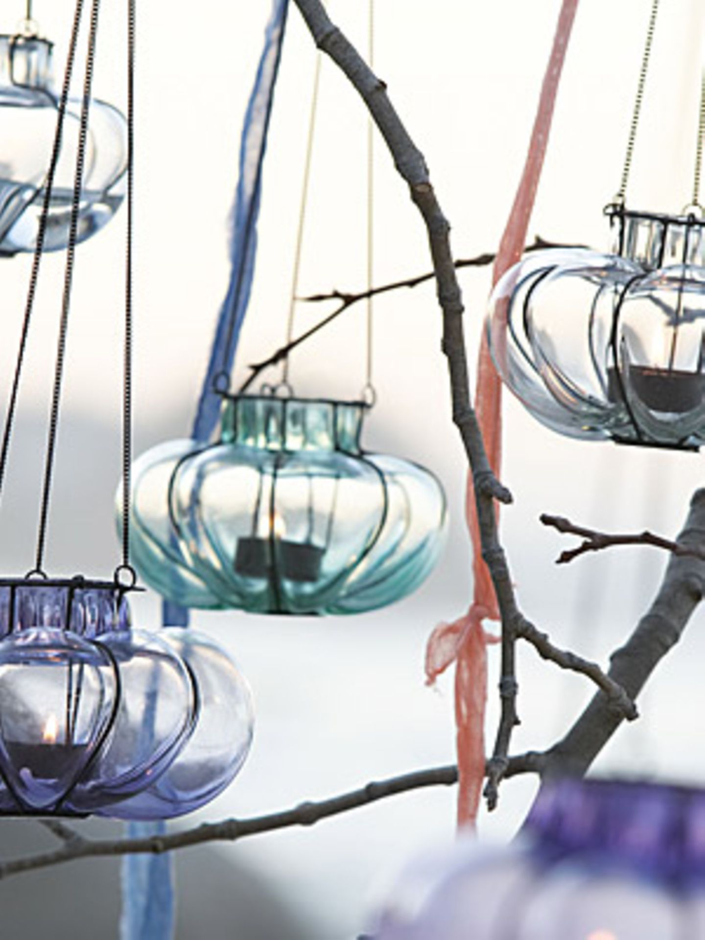 Die kleinen, weich geformten Hängewindlichter aus Glas sind mit einem Metalldraht eingefasst und können an einer Metallkette aufgehängt werden. In verschiedenen Farben bei Impressionen erhältlich. Um 10 Euro.