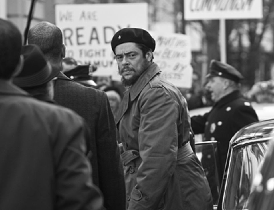 Che - Revolución Che Guevara (Benicio Del Toro) wird bei seiner Ankunft vor dem UN-Gebäude in New York von mit Protesten gegen die kubanische Regierung empfangen.