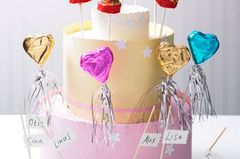 Auf dieser Torte haben wir gleich vier Sorten Cake Pops arrangiert: Dankeschön-Herzen mit buntem Papier, zweifarbige Platzkärtchen, weiße Hochzeits- und rote Geburtstagstorten. Und schon allein die selbst gebastelte Torte ist ein toller Blickfang! So könnt ihr sie nachbasteln: Das Grundgerüst ist aus Styropor - den kann man sich im Baumarkt zuschneiden lassen oder selbst mit einem Cuttermesser zurechtschneiden. Die erste Etage der Torte hat einen Durchmesser von 28 cm (Höhe 15 cm), die zweite einen Durchmesser von 22 cm (Höhe 15 cm) und die dritte einen Durchmesser von 12 cm (Höhe 5 cm). Die Umrisse lassen sich ganz einfach mit Hilfe verschiedener Springformen aufzeichnen. Farbigen Fotokarton im selben Durchmesser wie die Tortenböden zuschneiden und mit Styroporkleber auf die Oberseite der der Tortenböden kleben. Die Löcher für die Cake Pops am besten mit einem spitzen Gegenstand vorlochen. Aus verschiedenfarbigem Fotokarton drei Streifen in den folgenden Größen zuschneiden: 90x16 cm, 72x16 cm, 40x6 cm. Jeweils eine Seite der Streifen mit einer Wellenrandschere schneiden. Die Streifen um den jeweils passenden Tortenboden herumlegen und an den überstehenden Rändern zusammenkleben. Mit einem Motivstanzer farbige Papierblumen ausstanzen und aufkleben. Mit einer Wellenrandschere 0,5 cm hohe Zierleisten aus Fotokarton zuschneiden und festkleben. Für die Platzkarten schneidet ihr mit einer Zackenrandschere kleine Kärtchen aus Fotokarton zu (z. B. 5x3 cm) und schreibt mit einem Stift nach Wahl die Namen darauf. Die Kärtchen am Stiel des Cake Pops in der gewünschten Höhe festkleben. Zum Rezept: Cake Pops "Dankeschön-Herzen", Zum Rezept: Cake Pops "Platzkärtchen" und Zum Rezept: Torten-Cake-Pops Auf dieser Torte haben wir gleich vier Sorten Cake Pops arrangiert: Dankeschön-Herzen mit buntem Papier, zweifarbige Platzkärtchen, weiße Hochzeits- und rote Geburtstagstorten. Und schon allein die selbst gebastelte Torte ist ein toller Blickfang! So könnt ihr sie nachbasteln: Das Grundgerüst ist aus Styropor - den kann man sich im Baumarkt zuschneiden lassen oder selbst mit einem Cuttermesser zurechtschneiden. Die erste Etage der Torte hat einen Durchmesser von 28 cm (Höhe 15 cm), die zweite einen Durchmesser von 22 cm (Höhe 15 cm) und die dritte einen Durchmesser von 12 cm (Höhe 5 cm). Die Umrisse lassen sich ganz einfach mit Hilfe verschiedener Springformen aufzeichnen. Farbigen Fotokarton im selben Durchmesser wie die Tortenböden zuschneiden und mit Styroporkleber auf die Oberseite der der Tortenböden kleben. Die Löcher für die Cake Pops am besten mit einem spitzen Gegenstand vorlochen. Aus verschiedenfarbigem Fotokarton drei Streifen in den folgenden Größen zuschneiden: 90x16 cm, 72x16 cm, 40x6 cm. Jeweils eine Seite der Streifen mit einer Wellenrandschere schneiden. Die Streifen um den jeweils passenden Tortenboden herumlegen und an den überstehenden Rändern zusammenkleben. Mit einem Motivstanzer farbige Papierblumen ausstanzen und aufkleben. Mit einer Wellenrandschere 0,5 cm hohe Zierleisten aus Fotokarton zuschneiden und festkleben. Für die Platzkarten schneidet ihr mit einer Zackenrandschere kleine Kärtchen aus Fotokarton zu (z. B. 5x3 cm) und schreibt mit einem Stift nach Wahl die Namen darauf. Die Kärtchen am Stiel des Cake Pops in der gewünschten Höhe festkleben. Zum Rezept: Cake Pops "Dankeschön-Herzen", Zum Rezept: Cake Pops "Platzkärtchen" und Zum Rezept: Torten-Cake-Pops