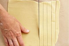 Alle 4 Teige übereinander gestapelt auf dem Backpapier für weitere 45 Minuten kalt stellen. Eine helle und eine dunkle Teigplatte mit einem Messer in gleichmäßig dicke Streifen schneiden. Jeden zweiten hellen Teigstreifen zur Hälfte nach oben legen. Alle 4 Teige übereinander gestapelt auf dem Backpapier für weitere 45 Minuten kalt stellen. Eine helle und eine dunkle Teigplatte mit einem Messer in gleichmäßig dicke Streifen schneiden. Jeden zweiten hellen Teigstreifen zur Hälfte nach oben legen.