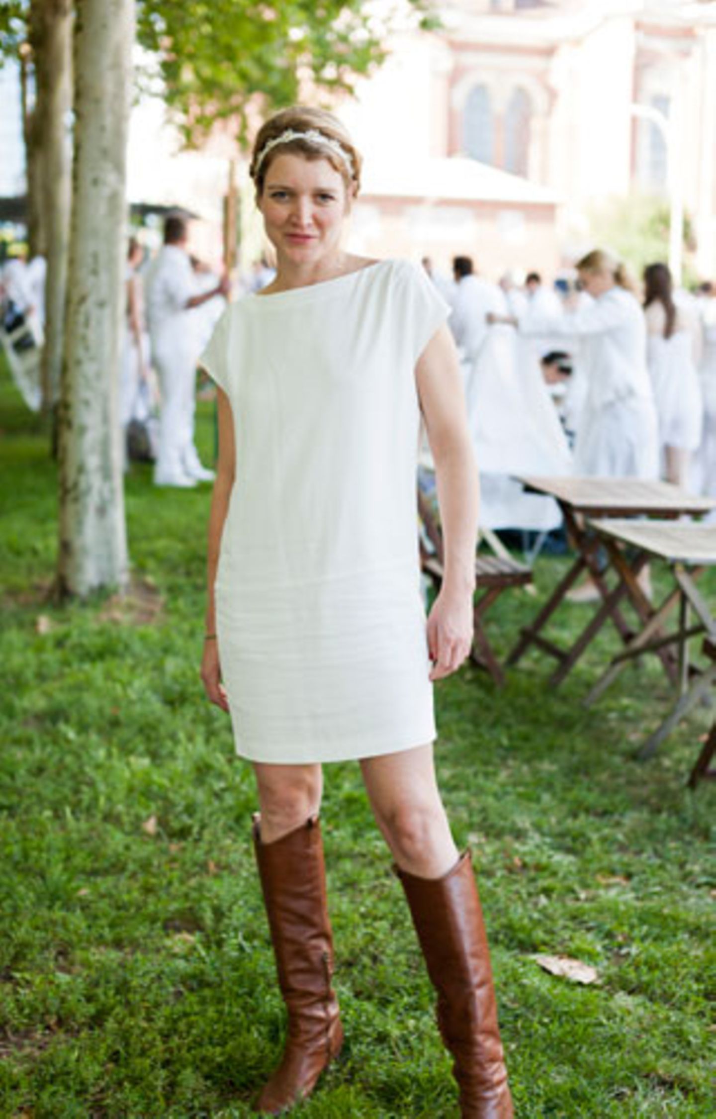Gelungene Kombination: Zum schlichten weißen Minikleid und Haarband passen auch derbe braune Lederstiefel.