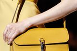 Schultertasche bei Gucci: ein sattes Gelb trifft auf robustes Strukturleder und raffinierte Verschlüsse.