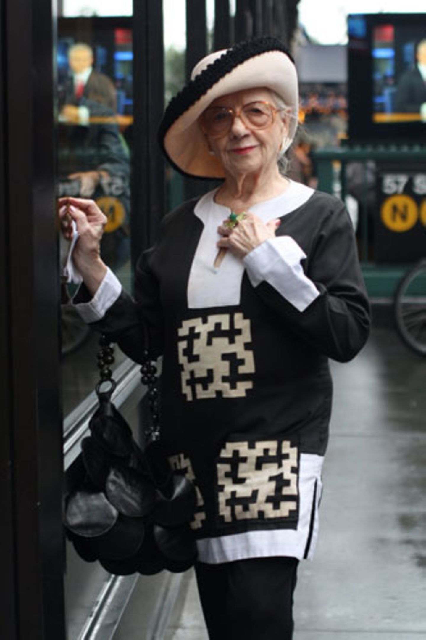 Schwarz, weiß und sehr elegant: Zur gemusterten Tunika trägt diese New Yorkerin einen Hut mit schwarzer Borte, eine schwarze Tasche und eine übergroße Brille.