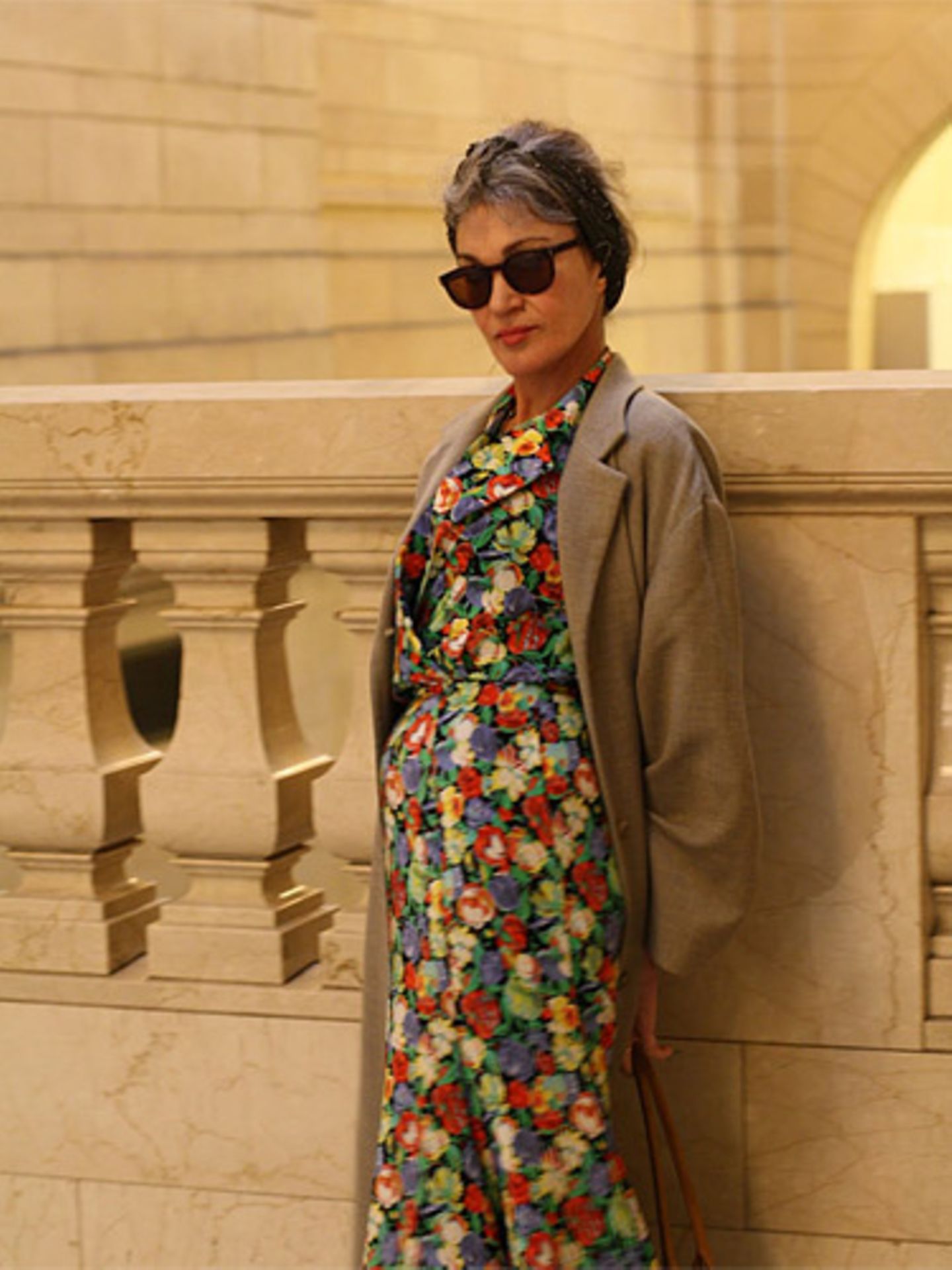 Jenny wurde in der Grand Central Station fotografiert: Sie trägt ein Blumenkleid, eine Kamelhaarjacke und eine Sonnenbrille von Ray Ban.