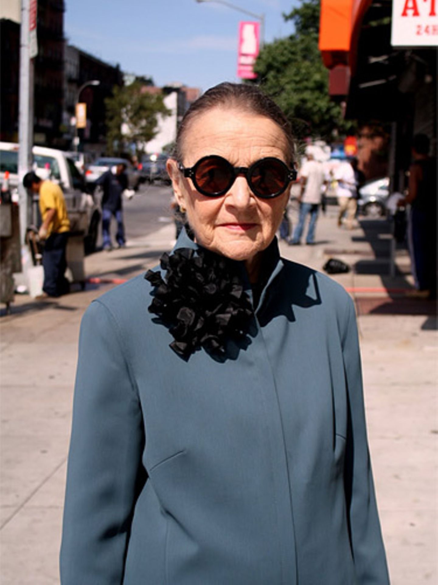 Ihre streng geschnittene graue Jacke verziert diese New Yorkerin mit einer auffälligen schwarzen Rüschenbrosche.