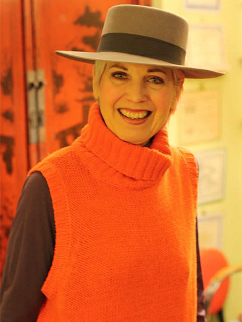 Debra ist Künstlerin und liebt es, mit Farben und Materialien zu spielen. Was sie auch tut, sie tut es mit Stil - ins Kino gehen zum Beispiel. Für diesen Anlass greift sie zum Hut und einem orangefarbenem Pullunder.