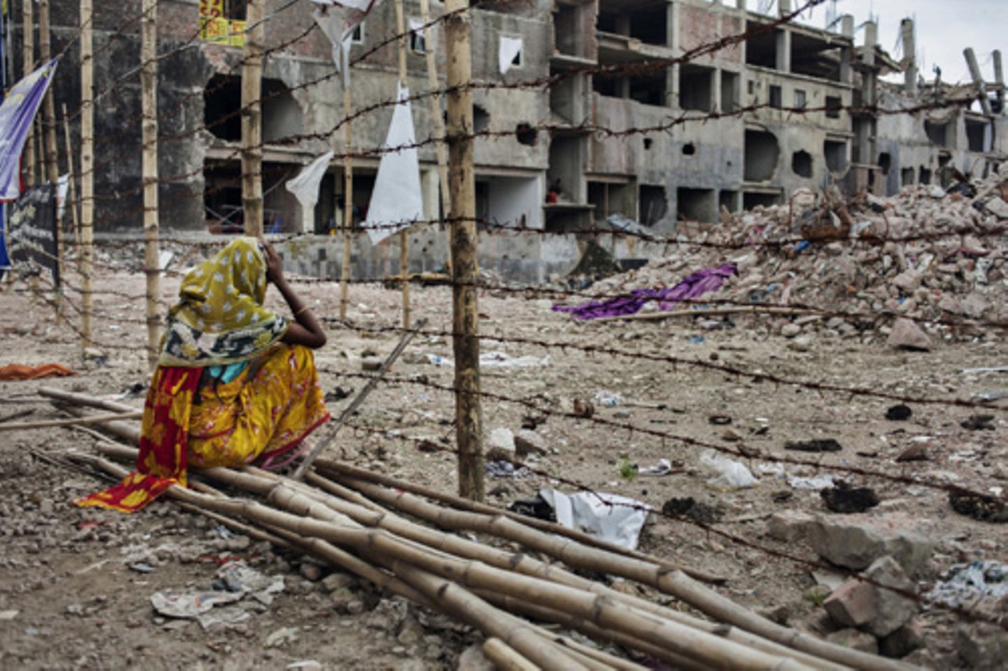 Vor den Trümmern der eingestürzten Fabrik wartet eine Mutter im Juli 2013 immer noch auf die Rückkehr ihrer Tochter Rina (18). © Taslima Akhter