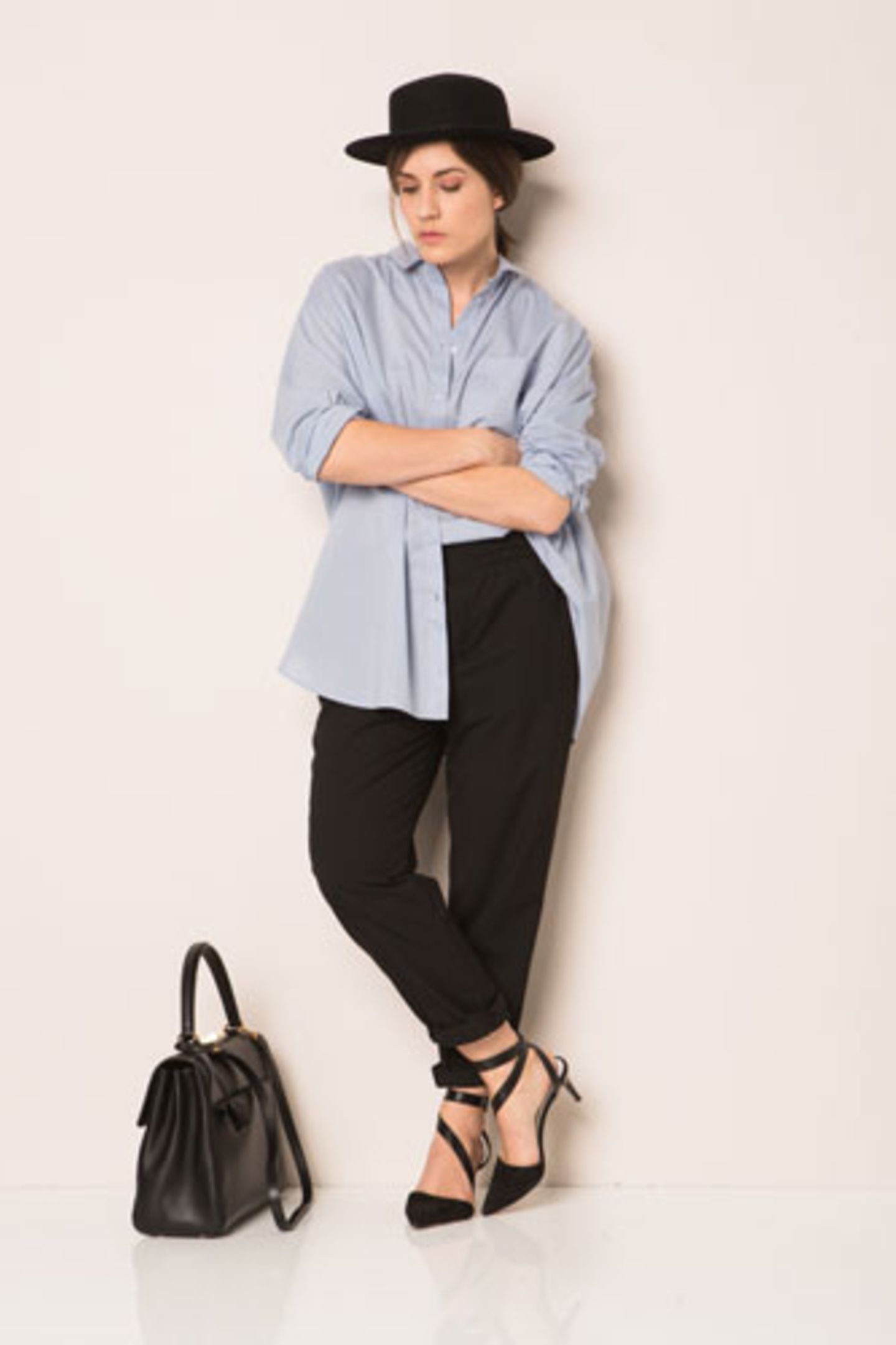 Bloggerin Carola von Vienna Wedekind wählte für ihren ersten Look ein blaues Herrenhemd und eine klassische schwarze Hose. Als Stilbruch kombinierte sie dazu feminine Pumps und einen markanten Hut.