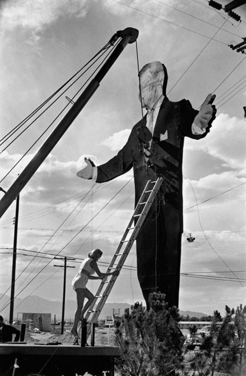 "Tropicana Hotel, Las Vegas, USA, 1957": Der gigantische Papp-Mann mag größer sein - aber diese Frau, die unbeeindruckt an ihm hochklettert, ist ohne Frage lässiger.