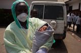Während die Aufklärungshelfer ihr Seminar verlassen, steht ein Arzt mit einem Neugeborenen vor der "Star of the Sea"-Klinik im Slum von West Point. Selbst im Angesicht der Ebola-Epidemie geht das Leben weiter.