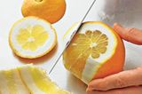 Die Orange zum Filetieren auf eine der flachen Seiten stellen. Dann mit einem sehr scharfen Messer die Schale vorsichtig so dick abschneiden, dass die weiße Haut vollständig mit entfernt wird.