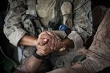 Eine amerikanische Soldatin hält die Hand eines verletzten US-Marines.