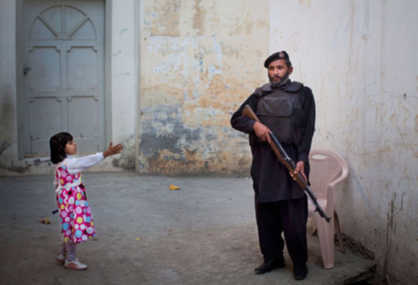 Ein junges Mädchen grüßt einen pakistanischen Polizisten.