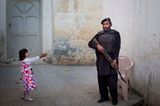 Ein junges Mädchen grüßt einen pakistanischen Polizisten.