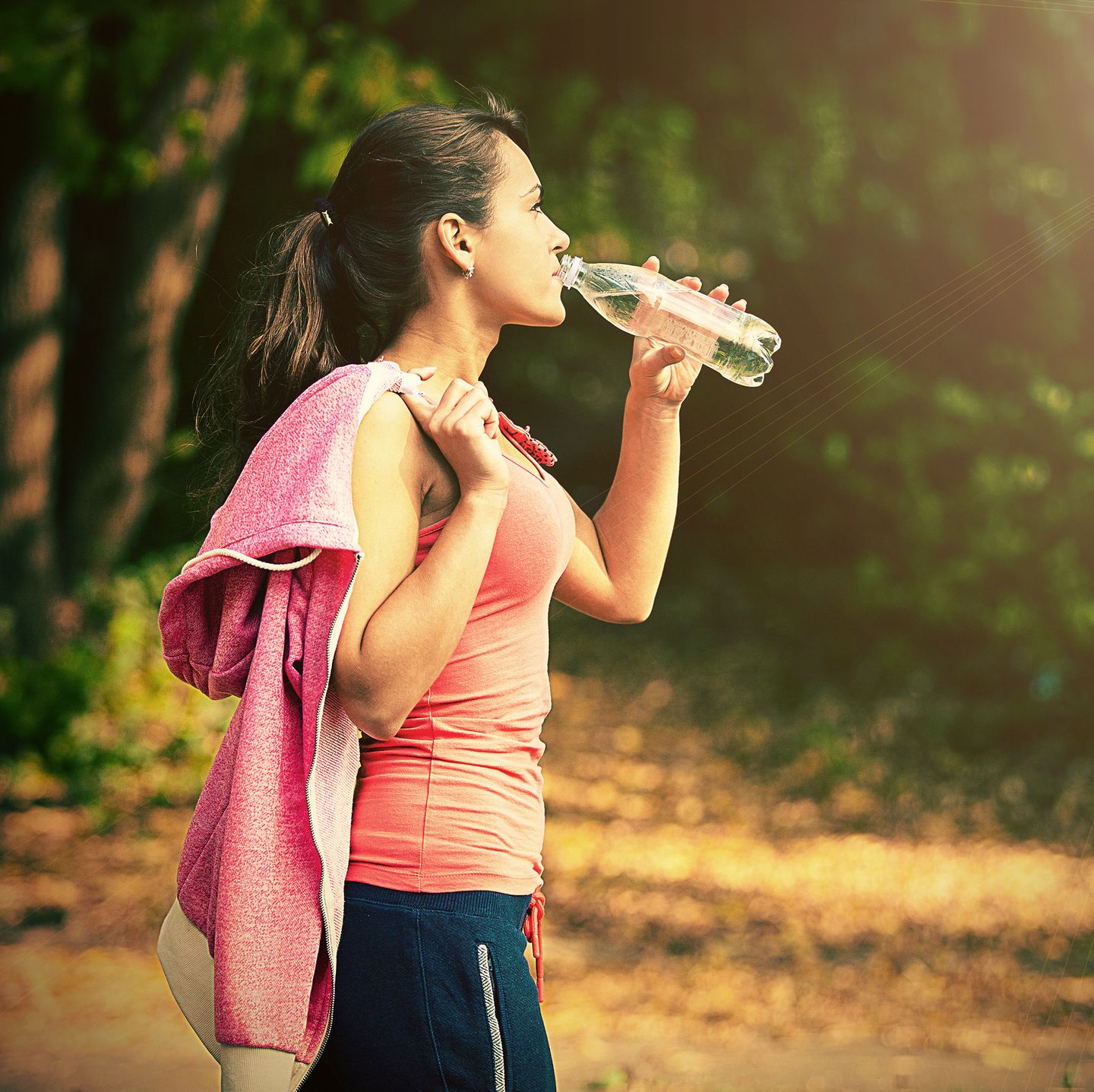 Gesunde Ernährung: Frau im Sport-Outfit trinkt Wasser aus der Flasche