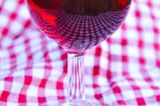 Mediterrane Diät: Ein Glas Rotwein auf karierter Tischdecke