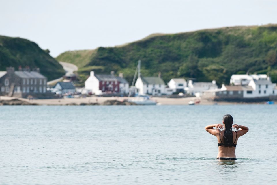 Hartgesottene Wales-Reisende gehen baden: Anna vor der Kulisse des Dörfchens Porthdinllaen auf der Halbinsel Llyn