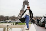Streetstyle: Eine Frau trägt Sneakers und Stoffhose vor dem Eiffelturm