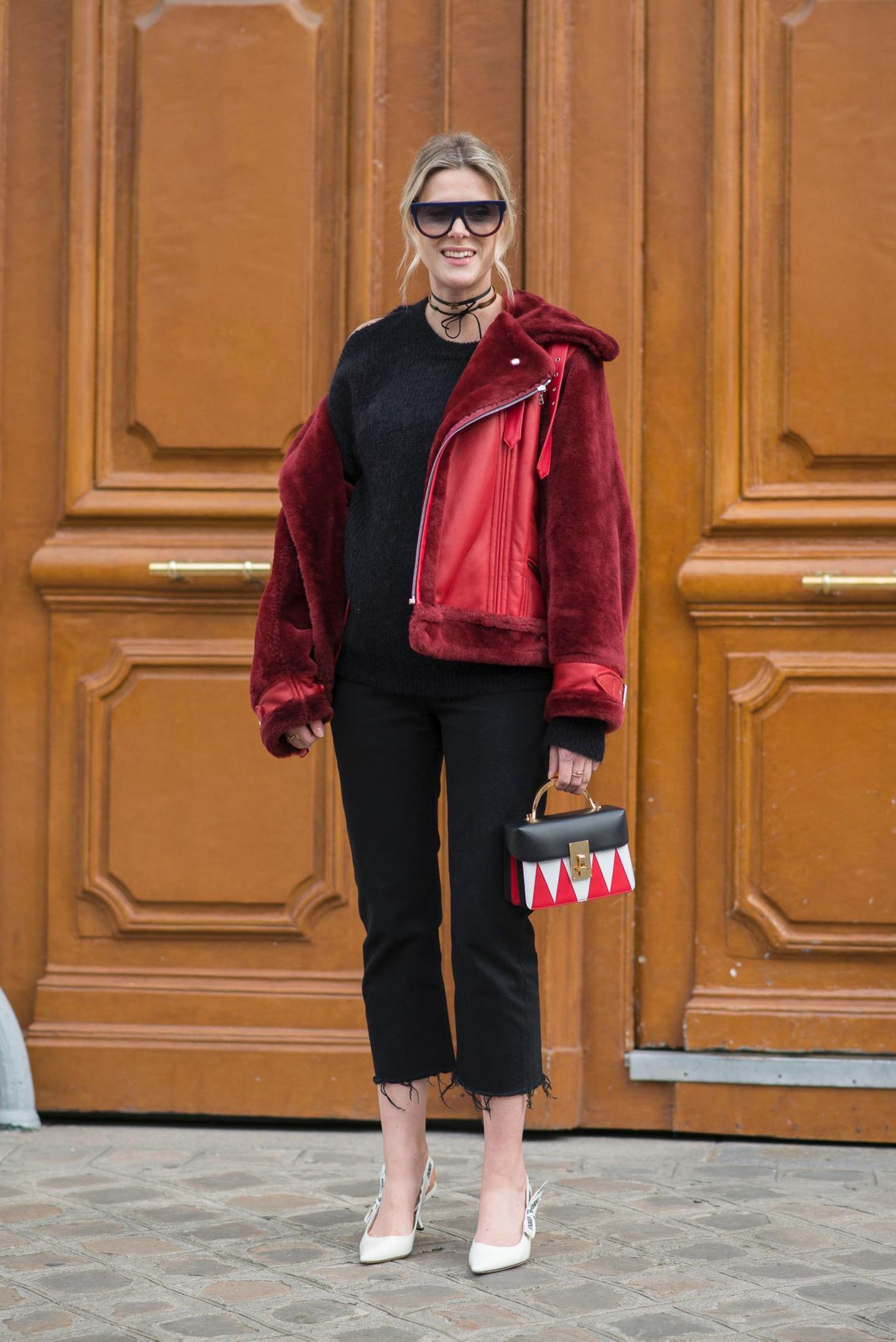 Bloggerin trägt schwarzes Outfit zu roter Lammfelljacke