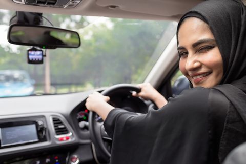 Eine Frau mit schwarzem Kopftuch am Steuer eines Autos.