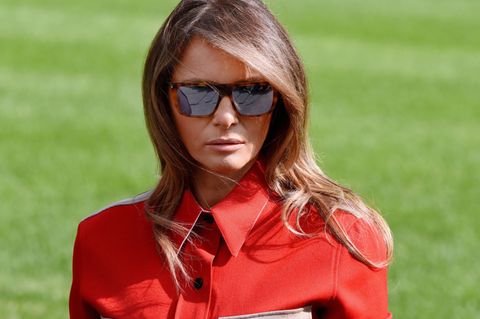 Melania Trump mit Sonnenbrille und hochgeschlossenem roten Outfit.