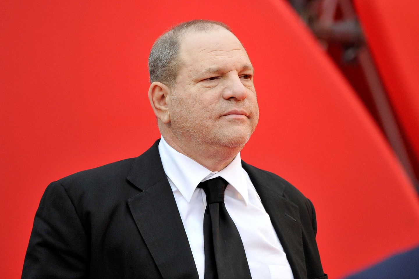 Harvey Weinstein im Anzug vor einem roten Hintergrund