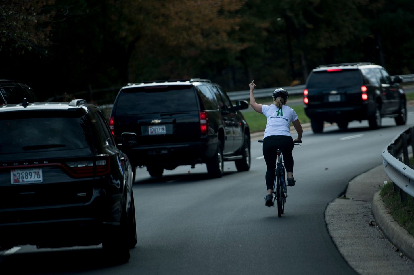 Juli Briskman auf einem Fahrrad. Sie zeigt dem vorbeifahrenden Donald Trump den Mittelfinger.