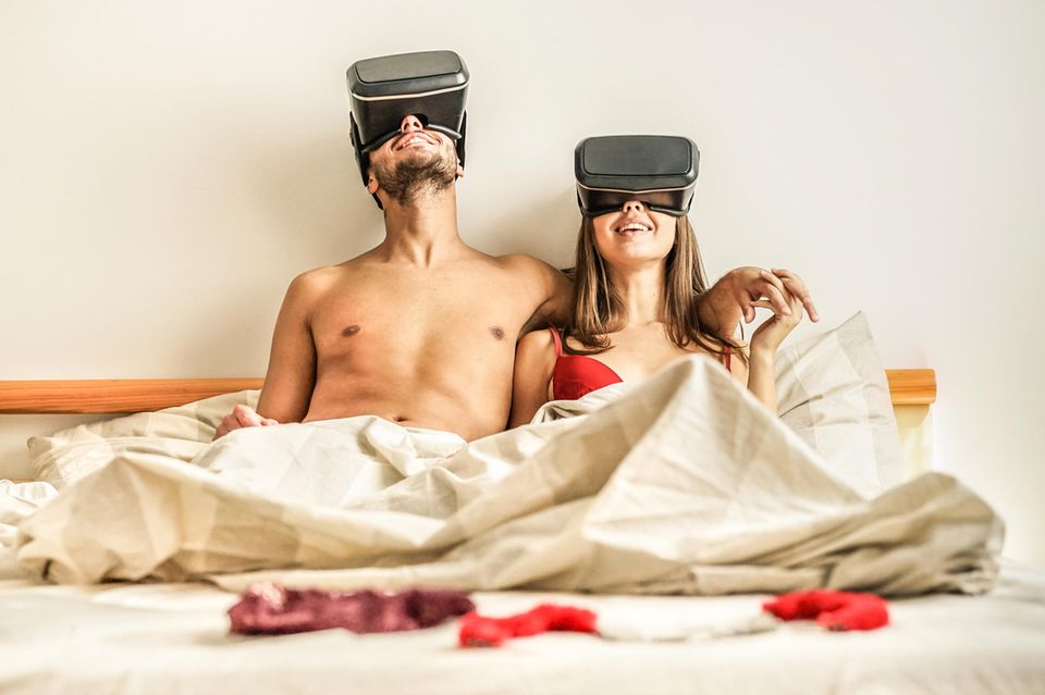 VR Porn: Paar sitzt mit VR-Brillen im Bett