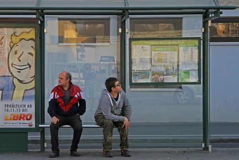Bußgeldbescheid: Zwei Menschen warten an einer Bushaltestelle.