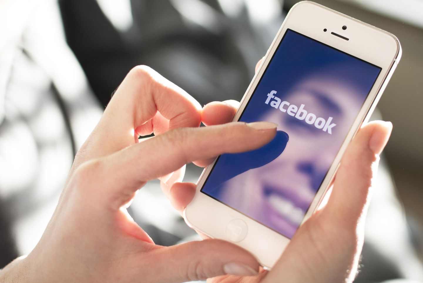 Facebook verlangt Selfie: Eine Person mit Smartphone, auf dem sich das Gesicht spiegelt
