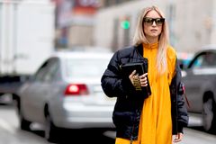 Maxikleid und Daunenjacke kombinieren Frau trägt gelbes Maxikleid und schwarze Daunenjacke