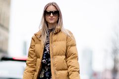 Blumen-Maxikleid mit Daunenjacke kombinieren Frau trägt Blumenkleid und Daunenjacke