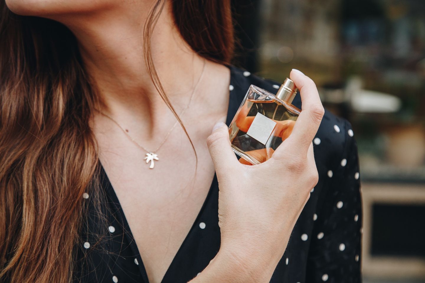 Frau sprüht sich Parfum auf die Haut