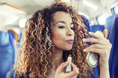 Frau schminkt sich im Zug