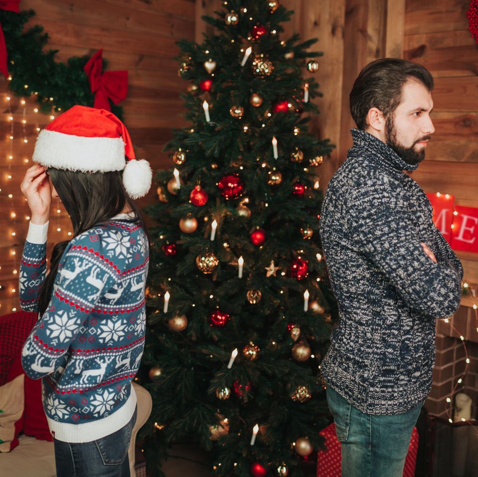 Streit zu Weihnachten: Paar vor dem Weihnachtsbaum