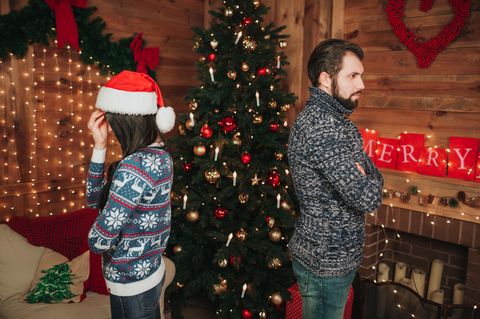 Streit zu Weihnachten: Paar vor dem Weihnachtsbaum
