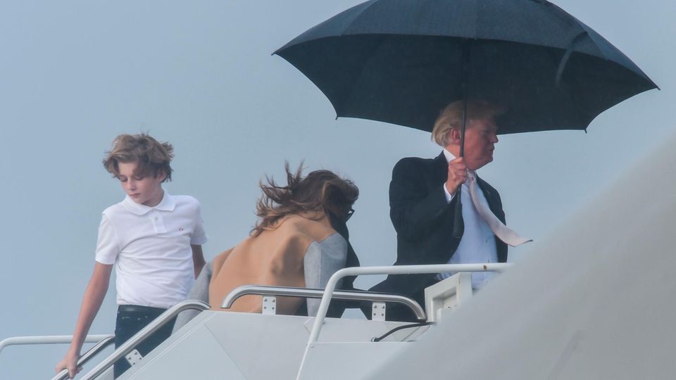 Donald Trump, Sohn Barron und Gattin Melania. Und ein Regenschirm.