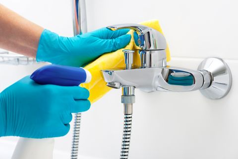 Bad putzen: Dusche und Wasserhahn mit Putzmittel reinigen