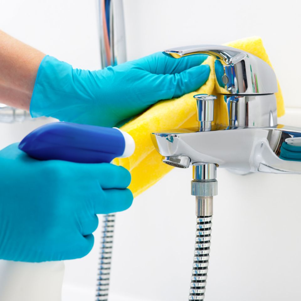 Bad putzen: Dusche und Wasserhahn mit Putzmittel reinigen