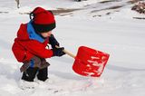 Kind mit Stiefeln  im Schnee mit Schippe