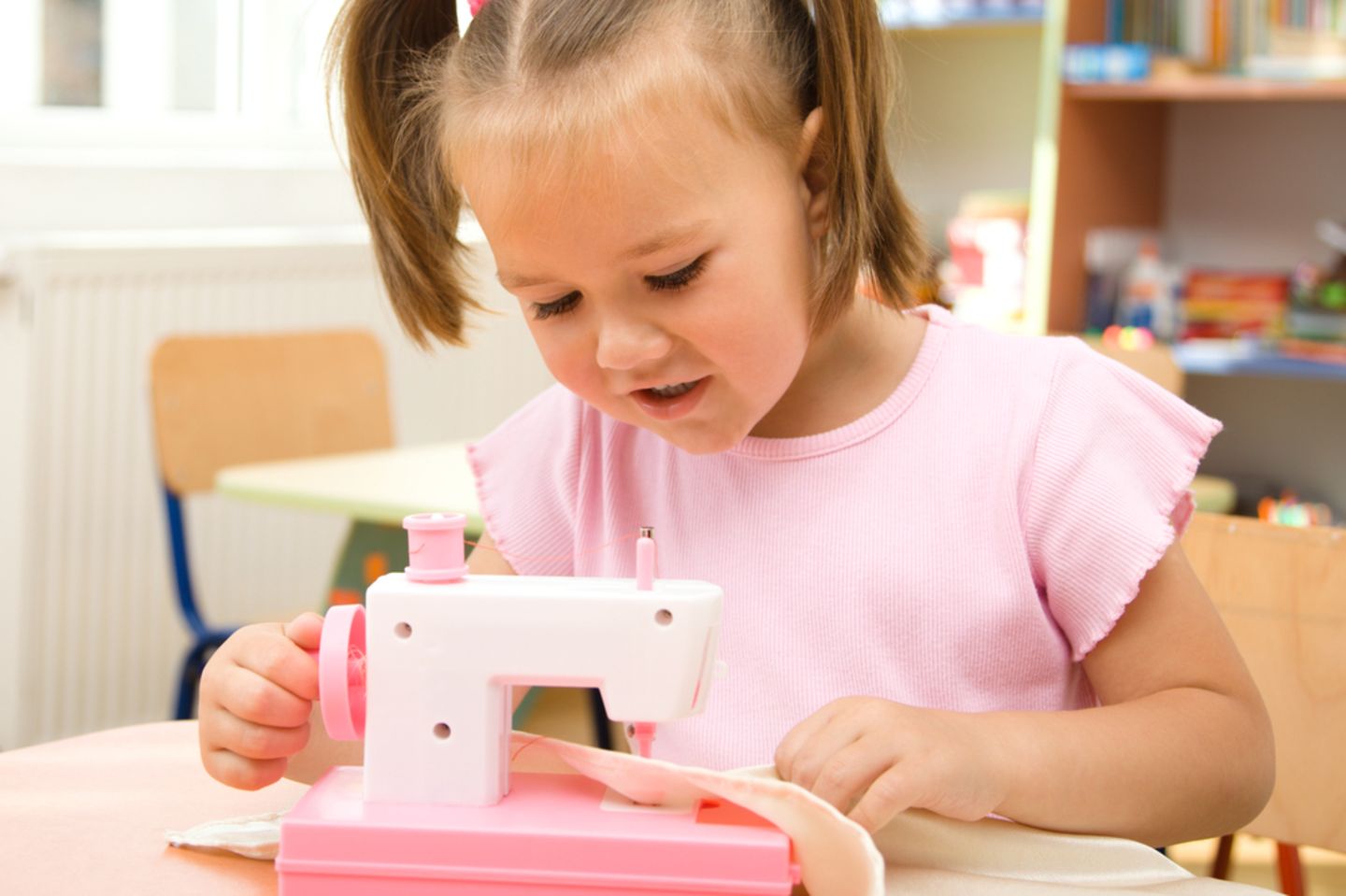 Nähen mit Kindern: Mädchen sitzt an Nähmaschine