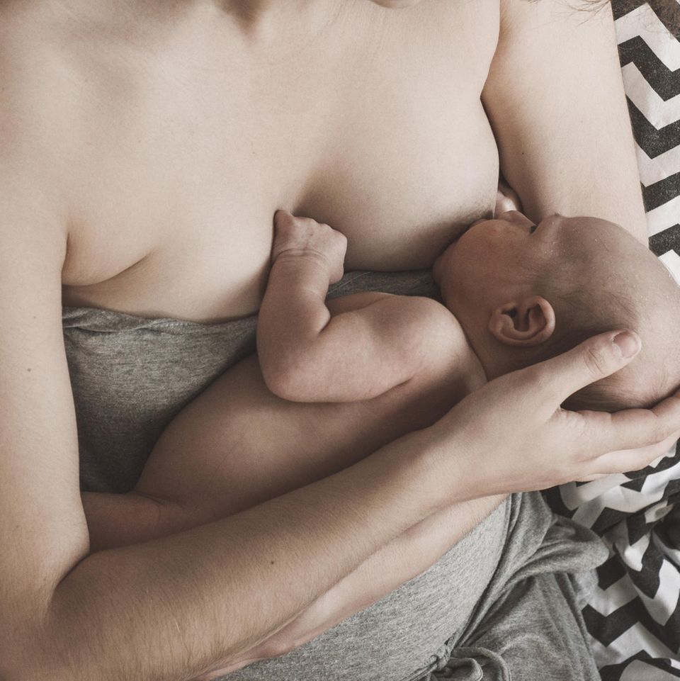 Medizin: Eine Frau hält ihr Baby an ihre Brust zum Stillen