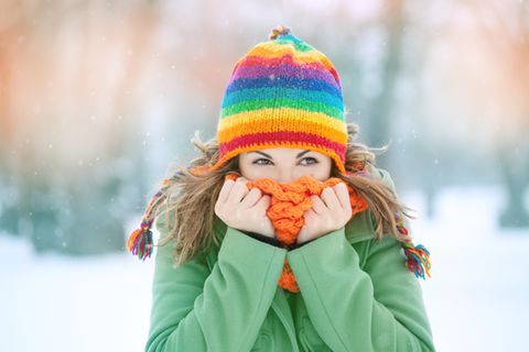 Frieren: Frau in Mütze steht im Schnee