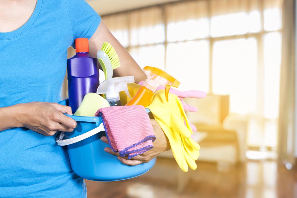 Studie: Eine Frau mit einem Putzeimer voll Reinigungsmitteln und Putzutensilien